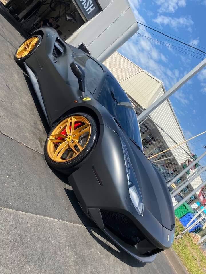 Matte black Ferrari with gold wheels after professional detail
